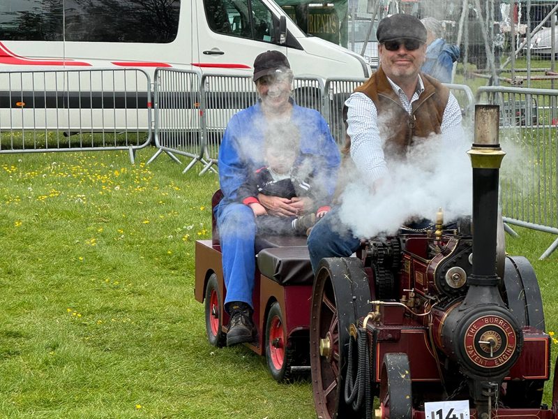 Nellie setting off in a cloud of her own steam, passengers smiling on the trailer behind